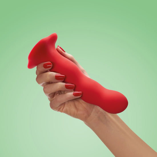 Woman's hand holding Fun Factory's Bouncer red dildo